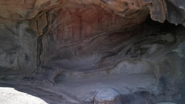 Cinematic shot exploring the ancient Great Murals cave paintings on a rock shelter wall in the Sierra de San Francisco, Baja California Sur, revealing prehistoric indigenous rock art