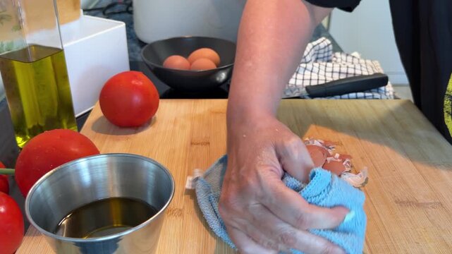 Female hand using a blue microfiber cloth to wipe and disinfect a wooden surface. 