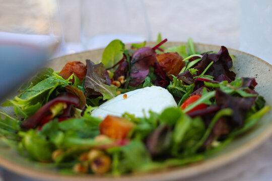 A colorful Mediterranean salad with fresh greens, tomatoes, and soft cheese served outdoors in Greece, celebrating local flavor and summer freshness.