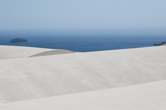 Smooth white architectural curves meet the deep blue Aegean Sea in Greece, forming a minimalist composition of Mediterranean light and calm.
