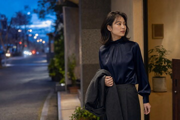 Fototapeta premium 夕方のレストラン入口に立つ濃紺ブラウスの女性