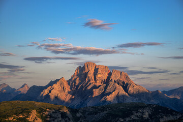 Beautiful alpine landscape featuring a sunlit mountain summit during the golden hour, perfect for travel and nature themes. © marcodenaro