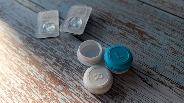 Open contact lens case with blister packs on wooden surface. 