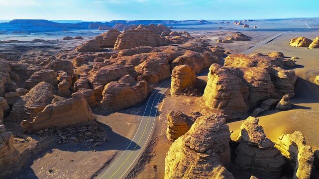 Winding asphalt road through yardang landform rock formations in Xinjiang, China. Aerial landscape view suitable for travel, geology, and transportation concepts.