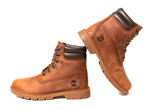 Pair of brown Timberland leather boots arranged dynamically on white background.