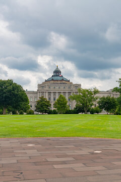 Vertical view of the Library of Congress beyond lawn and stone plaza.