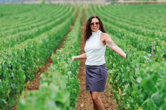 Woman standing between vineyard rows in Beaune, Burgundy, France, surrounded by lush grapevines in one of the world's most celebrated wine regions.