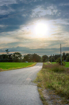 Country Road Lead Away in Distance Under Setting Sun