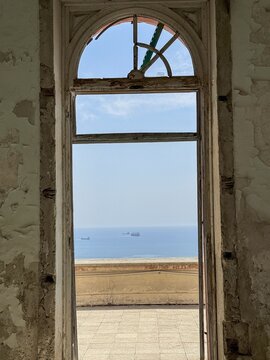 Historic arched window overlooking serene coastal sea landscape