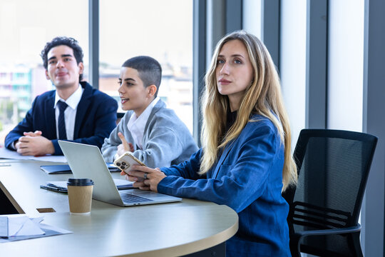 Focused businesswoman holding and reviewing a financial report document with colleagues during a corporate meeting in a modern office.