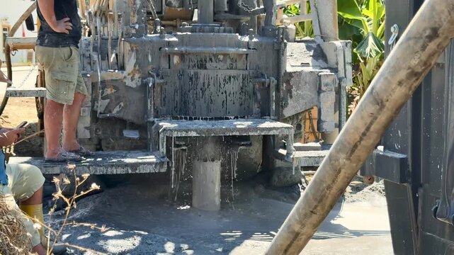 A well drilling operation in Turkey, surrounded by banana plantations and residential complexes in the background.