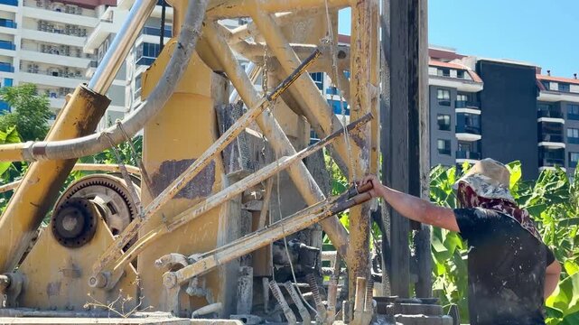 A well drilling operation in Turkey, surrounded by banana plantations and residential complexes in the background.