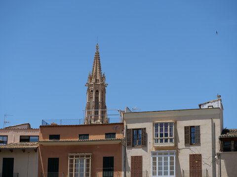 Gothic Church Tower Rising Above Mediterranean Town Buildings