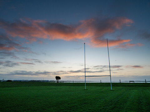 Silhouette of a tall goal posts in a field against dramatic sunrise sky. National sport of Ireland equipment. Rugby, camogie, hurling training ground. Calm and relaxing mood.
