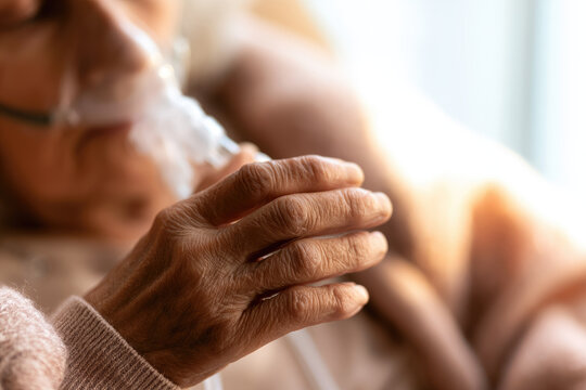 Elderly hand holding oxygen nasal cannula in nursing home near window with soft daylight and warm care mood