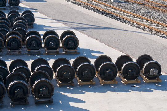 Train wheelsets stored in row outside railway maintenance facility near tracks