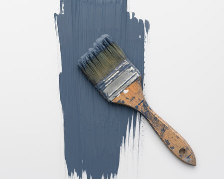 Vintage worn paintbrush on blue paint stroke over white background