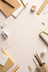 Naklejka premium Back to school vertical flat lay with neutral stationery, notebooks and pencils on a pale desk with copyspace in the middle