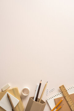Back to school flat lay with neutral stationery, pencils, notebook and ruler on vertical workspace with blank space