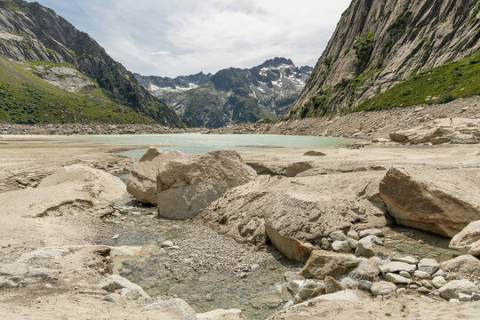 Guttannen, Switzerland. Low water level at Gelmersee reservoir with exposed shoreline and alpine mountains in the Bernese Alps