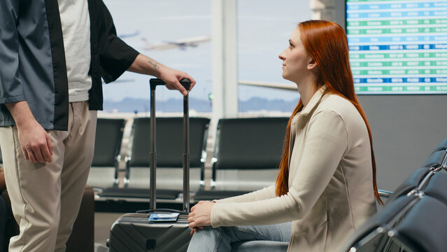 Man and woman say goodbye in an airport lounge before a flight, sharing a bittersweet farewell that conveys love, sadness and emotional separation.