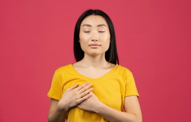 Obraz premium Calm Asian Woman With Closed Eyes Practicing Mindfulness And Deep Breathing At Home, Relaxing And Focusing On Inner Peace In Cozy Environment. Promoting Mental Wellness And Calmness.