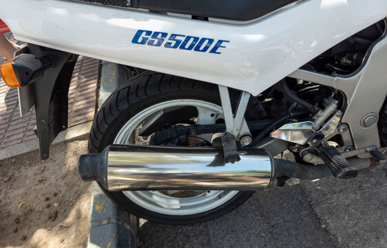 TAVERNES BLANQUES, SPAIN - JUNE 14, 2026.Classic white Suzuki motorcycle rear wheel and chrome exhaust pipe on display in Spain