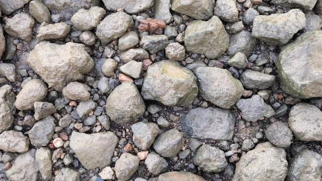 Natural river rocks and pebbles forming textured stony surface with varied shapes, earthy colors, outdoor background composition.