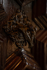 Classic historic building carved dark oak wood door with antique bronze handle close up.  © Yar