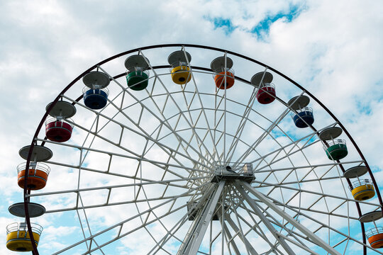 Ferris wheel with colorful cabins against partly cloudy sky