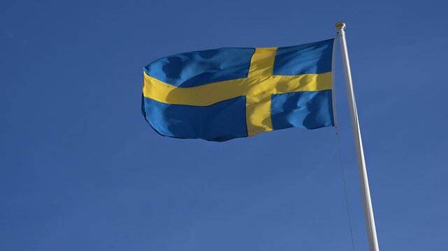 Sweden Swedish flag flying in the wind. The national flag of Sweden waving proudly against the sky.