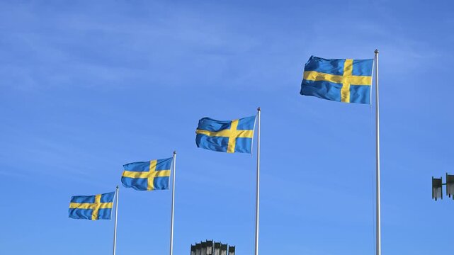 Swedish flags flying in the wind. The national flags of Sweden waving proudly against the sky.