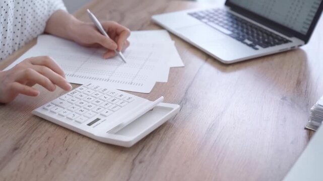 Office worker balancing budget with calculator and laptop on a desk. Bookkeeping, finance audit and taxes