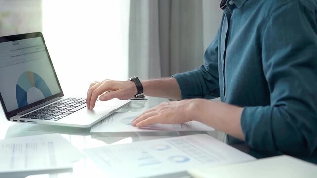 Professional working at laptop with data analysis charts. Businessman analyzing statistical data on a laptop next to business reports. Business concept