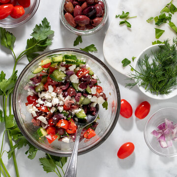 A tossed mediterranean salad with ingredients all around.