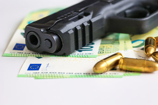 Close-up of a handgun and bullets resting on euro banknotes. Concept of financial crime, armed violence, illegal money, organized crime, security threats and criminal activity.