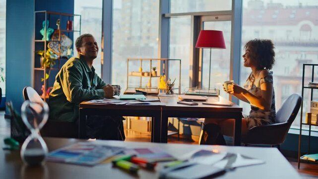 Two young people talking over coffee sunny loft office. Friends discuss project.