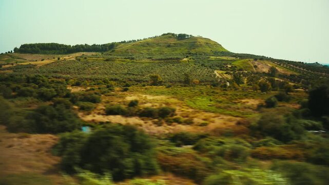 A landscape of Calabrian hills and plains seen from a train window