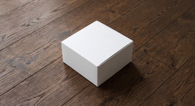 A square white cardboard box mockup placed on a dark brown wooden plank floor with soft lighting and subtle shadows.