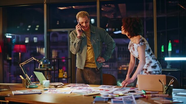 Coworkers reacting to phone news office night. Man and woman shocked at bad news
