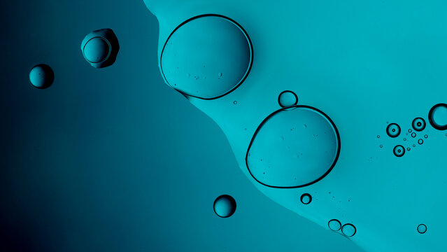 Oil bubbles floating on blue water surface macro