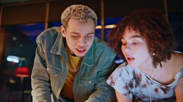 Frustrated coworkers reviewing mood board photos in night office design studio