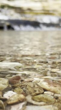 closeup of water in stream flowing over smooth river rocks