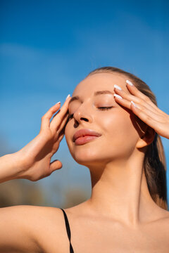 Young woman relaxing under warm sunlight with healthy skin. Beauty woman enjoying fresh outdoor glow naturally. Summer skincare concept.