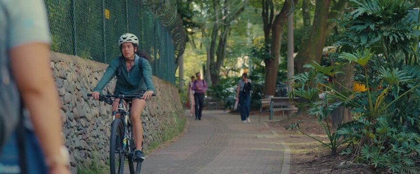 People Walking and Cycling on a Shady Green Park Path