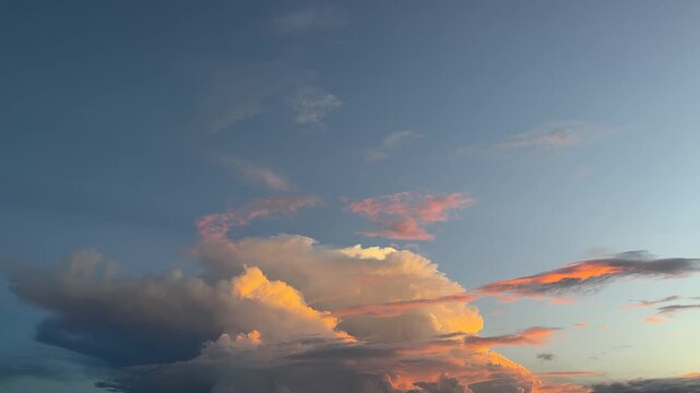 Dramatic clouds glowing orange at sunset in blue evening sky