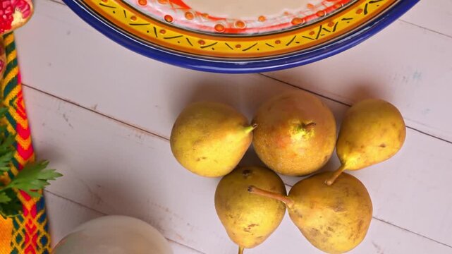 Mexican food flatlay with talavera plate, fresh pears and nogada salsa. Ingredients to prepare chile en nogada