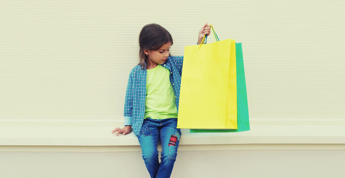 Little girl child with shopping bags posing on city street
