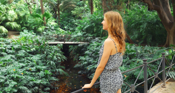Happy smiling young woman enjoying nature in forest on tropical tree background