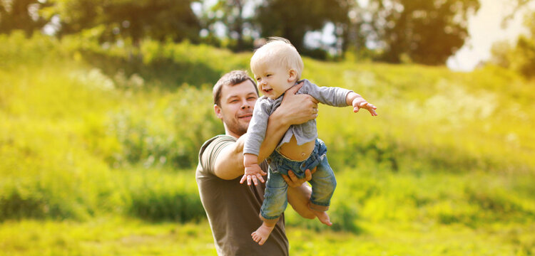 Happy father and son, joyful dad playing with child, holding on hands in the park